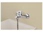 Mitigeur de douche mural chromé avec flexible, au-dessus d'un receveur de douche blanc.