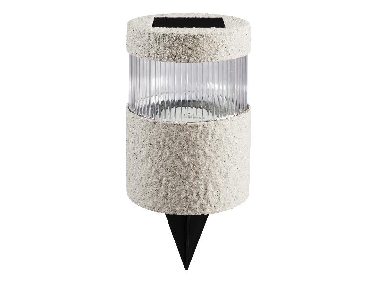 Lampe de jardin solaire avec un boîtier gris texturé et un abat-jour transparent nervuré.