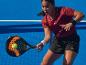 Femme jouant au padel avec raquette et balle sur un court bleu.