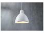 Een witte hanglamp tegen een betonnen muur.