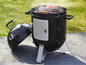 Un barbecue noir avec un couvercle, sur lequel du poisson et des légumes sont grillés.