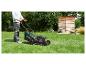Homme tondant la pelouse avec une tondeuse à essence Parkside dans un jardin.