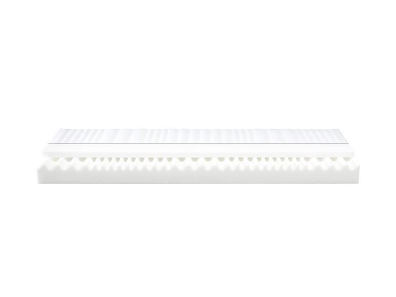 Een wit matras met een golvende schuimlaag en een gladde toplaag.