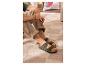 Homme en sandales vertes à deux brides et pantalon beige, assis sur un tapis.