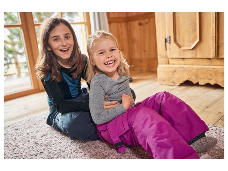 Twee meisjes lachen samen, één draagt een roze broek