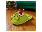 Pantoufles vertes Grinch avec bonnets de Noël sur un parquet en bois