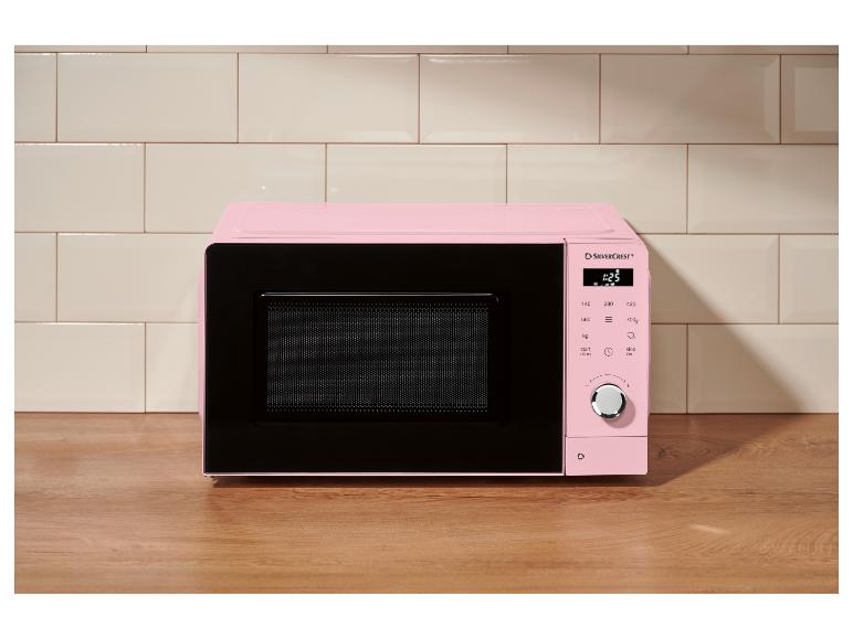 Roze magnetron met digitaal bedieningspaneel op een houten aanrecht, voor keukentegels.