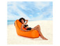 Een vrouw die ontspannen in een oranje opblaasbare ligstoel op het strand ligt.
