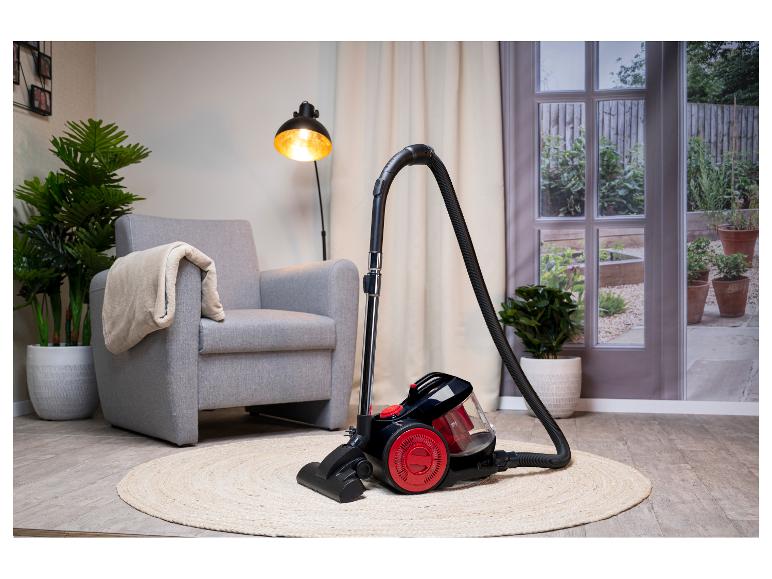 Aspirateur traîneau rouge et noir sur un tapis en jute dans un salon confortable.