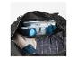 Open zwarte tas met tablet, toiletartikelen, notitieboekje, pen, telefoon en kleding.