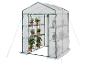 Serre portable avec plantes, couvercle transparent et bords verts.