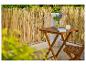 Bamboe schutting op balkon met houten tafel en stoel, bloemen en boek.