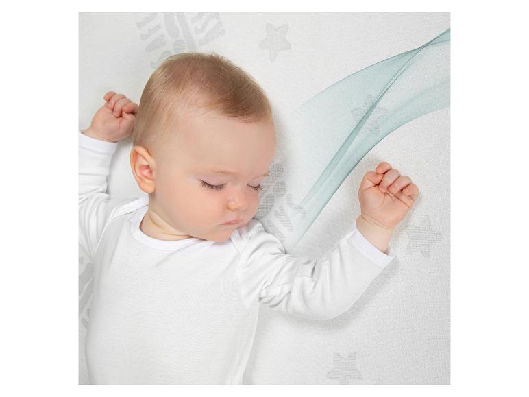Bébé dormant sur un matelas avec un motif d'étoiles et de vagues.