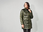 Une femme porte un long manteau matelassé vert.