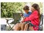 Vrouw en kind zitten op campingstoelen, buiten een boek lezend.