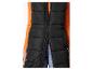 Zwart lang gewatteerd vest met een oranje shirt met lange mouwen en jeans.