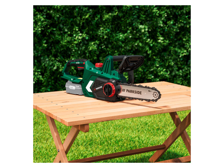 Een groene Parkside accu kettingzaag op een houten tafel.