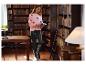 Vrouw in roze trui met hartjespatroon en zwarte imitatielederen legging houdt boeken vast in een bibliotheek.