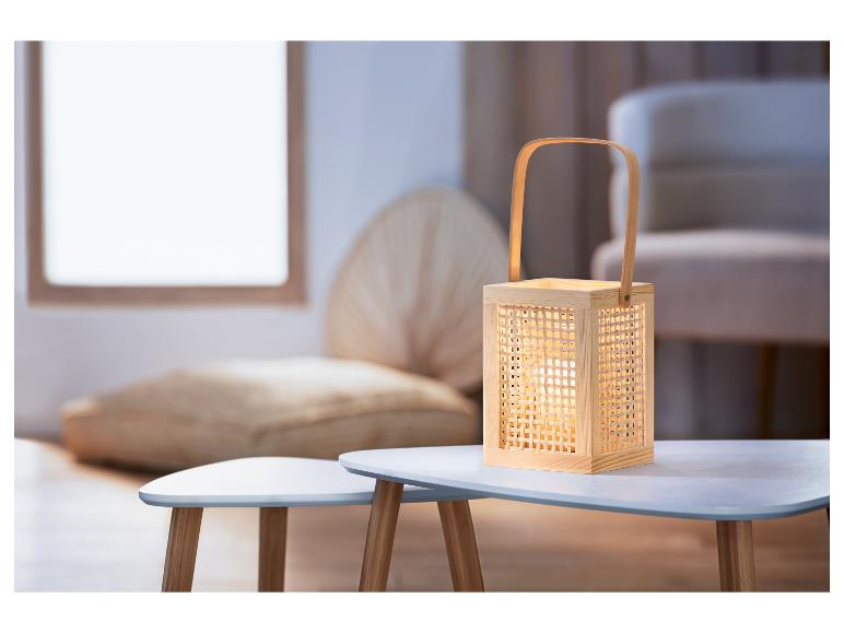 Een houten lamp met gevlochten patroon op een wit tafeltje.