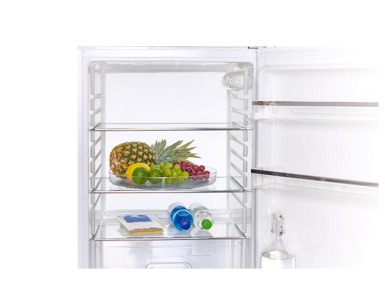 Réfrigérateur ouvert avec fruits, bouteilles d'eau et fromage.