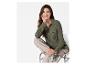 Een vrouw draagt ​​een groene blouse, beige broek en groene sneakers.