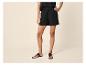 Femme en short noir et sandales plates, posant la main sur la hanche.