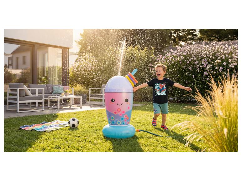 Garçon heureux jouant avec un arroseur de jardin en forme de bubble tea sur une pelouse ensoleillée.