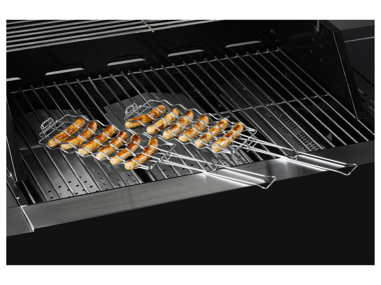 Gegrilde worstjes in een grillrooster op een zwarte grill.