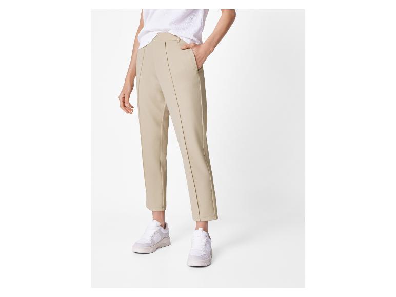 Vrouw in beige broek en witte sneakers.