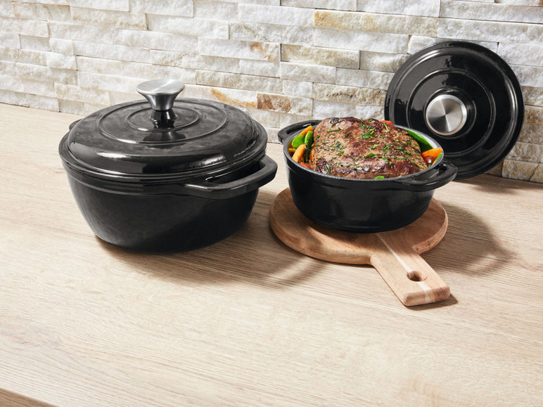 Deux casseroles en fonte noire avec un rôti et des légumes.