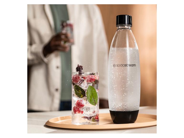 Une bouteille SodaStream et un verre de boisson pétillante aux baies et à la menthe.
