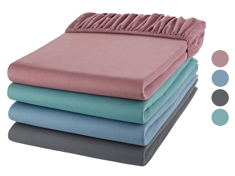 Une pile de draps-housses rose, bleu, gris et turquoise.