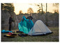Twee personen zetten een blauwe en een grijze tent op tijdens een kampeertrip.