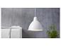 Een witte hanglamp boven een wit dressoir met een groene plant.