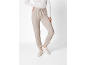 Vrouw in beige joggingbroek en witte trui, met lichte sneakers.