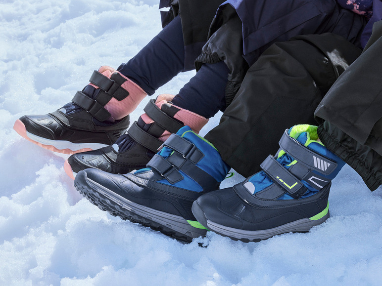 Drie paar zwarte winterschoenen met blauwe en roze details in de sneeuw.