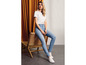 Een vrouw draagt een wit T-shirt, blauwe skinny jeans en witte sneakers.