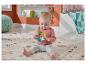 Bébé assis sur un tapis, jouant avec un hochet en forme de paresseux.