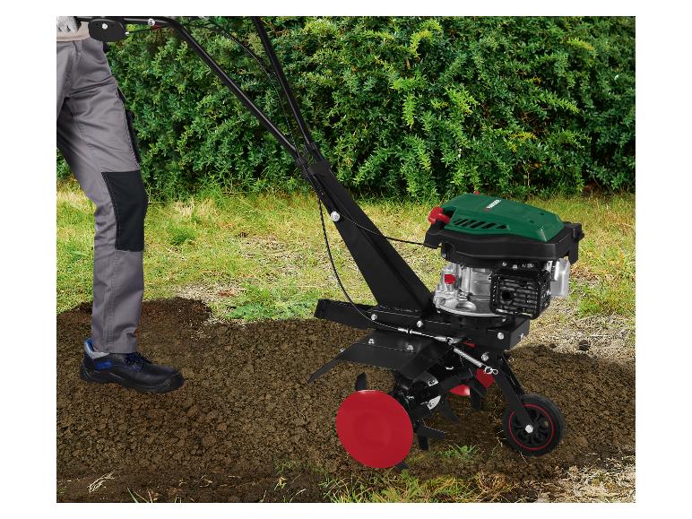 Personne utilisant un motoculteur thermique Parkside dans un jardin, cultivant le sol.