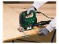 Een persoon zaagt een houten plank met een elektrische zaag, met beschermende handschoenen.