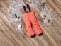 Oranje ski-broek met bretels op een houten vloer met sneeuw.