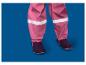 Pantalon de pluie rose pour enfant avec bandes réfléchissantes et bottes foncées.