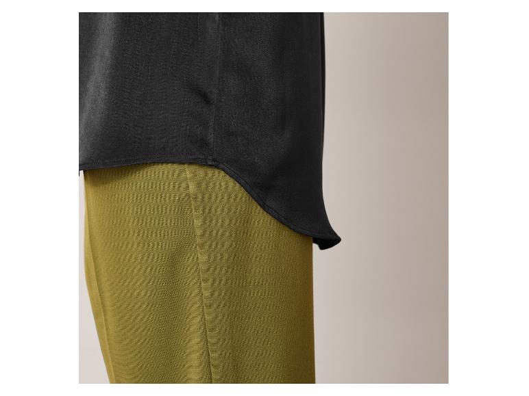 Zwarte blouse met lange mouwen en groene broek.