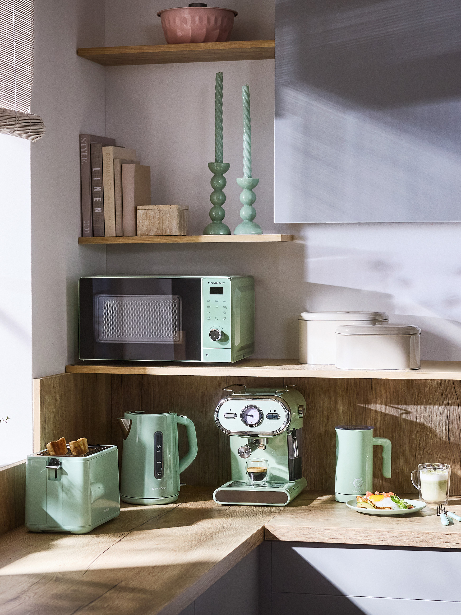 Keukenhoek met mintgroene apparaten: magnetron, broodrooster, waterkoker en espressomachine.