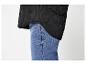 Veste matelassée noire sur un jean bleu.