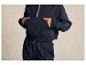 Een model draagt een blauwe hoodie en joggingbroek met een logo.