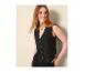 Vrouw in zwart gilet en zwarte broek, lachend en naar rechts kijkend.