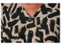 Detail van een beige jurk met een zwart-wit abstract print.