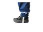 Close-up van een kinderbeen in een blauwe waterdichte broek met reflecterende streep en een grijze schoen.