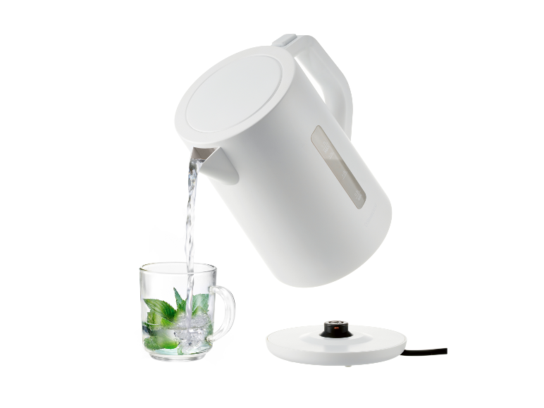 Une bouilloire blanche verse de l'eau dans une tasse à la menthe.